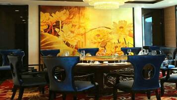 A dining area with a round table, blue chairs, and a large floral mural on the wall.