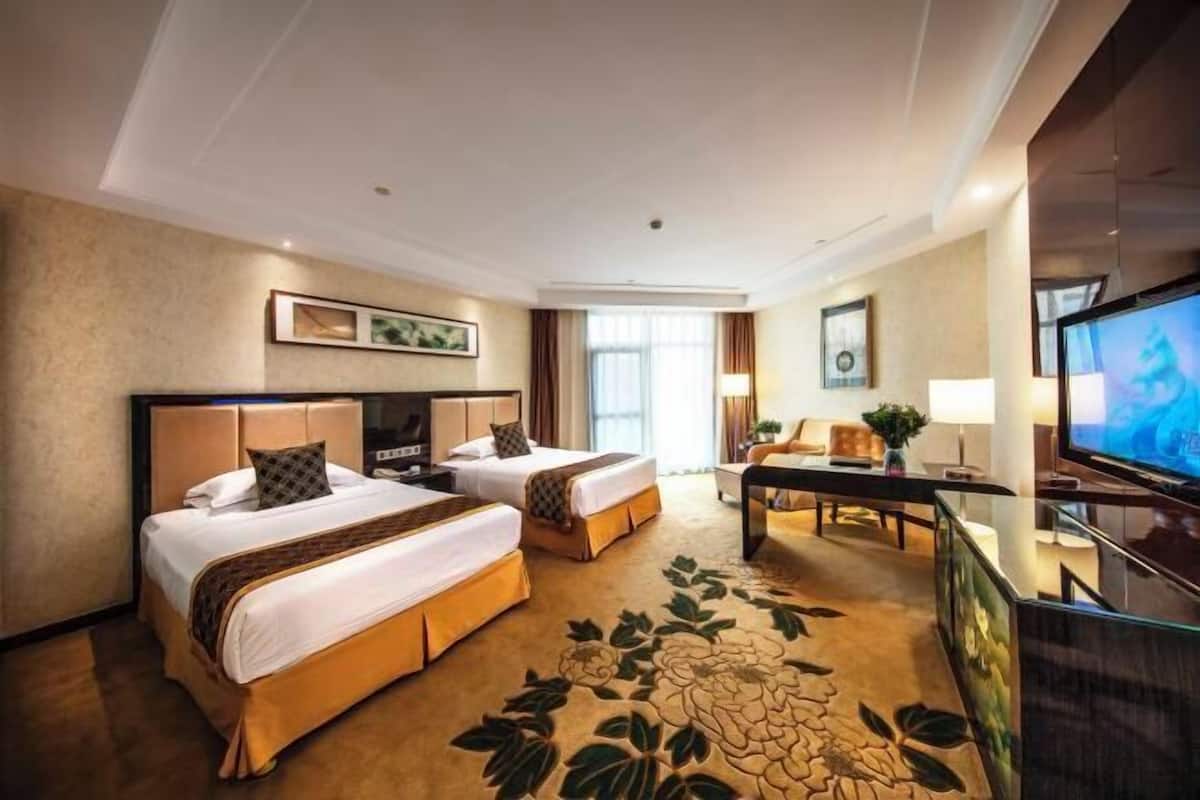 Een hotelkamer met twee bedden, een bureau, een televisie en een bloemenkleed.