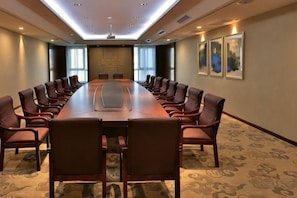 A conference room with a long table, chairs, a projector, and framed artwork on the walls. - Hong Wan Hotel (Pingshan)