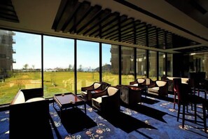 A modern hotel room with large windows, a view of a golf course, and a seating area with sofas and a table. - Hong Wan Hotel (Pingshan)