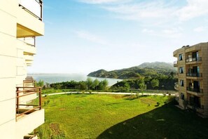 A building with a balcony overlooking a grassy area and a body of water.