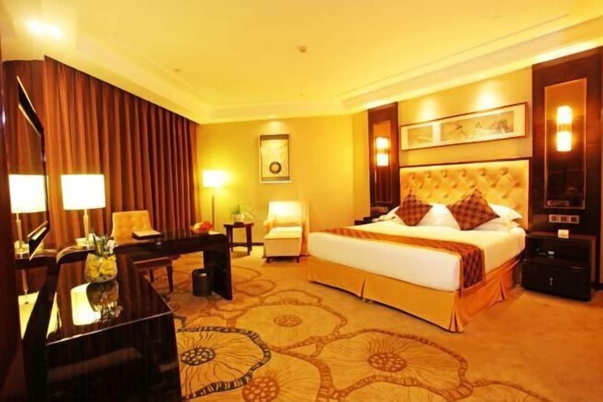 Een hotelkamer met een groot bed, een bureau, een stoel en een lamp.