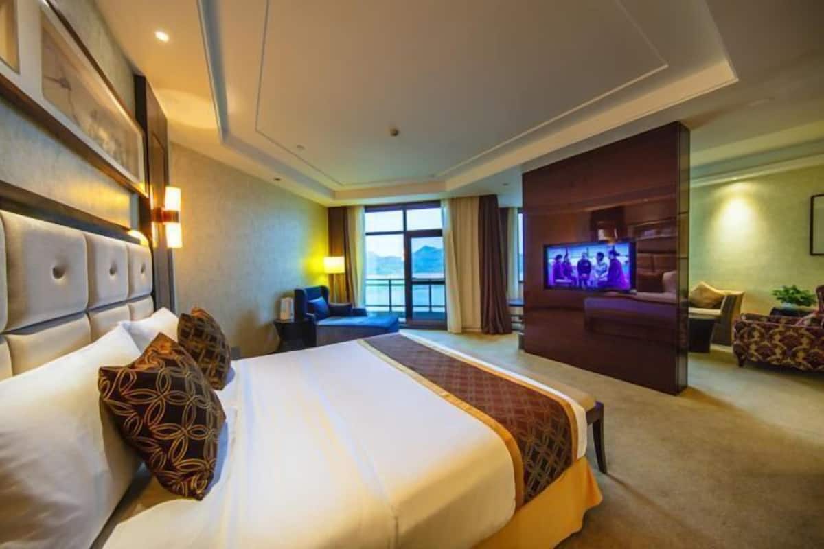 Een hotelkamer met een groot bed, een televisie, een zithoek en uitzicht op de omgeving.