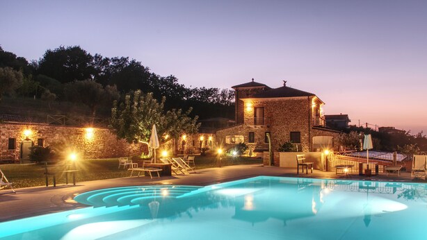 A swimming pool with lounge chairs and a stone building in the background.