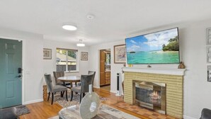 Una sala de estar con chimenea, televisor y comedor con sillas y mesa.