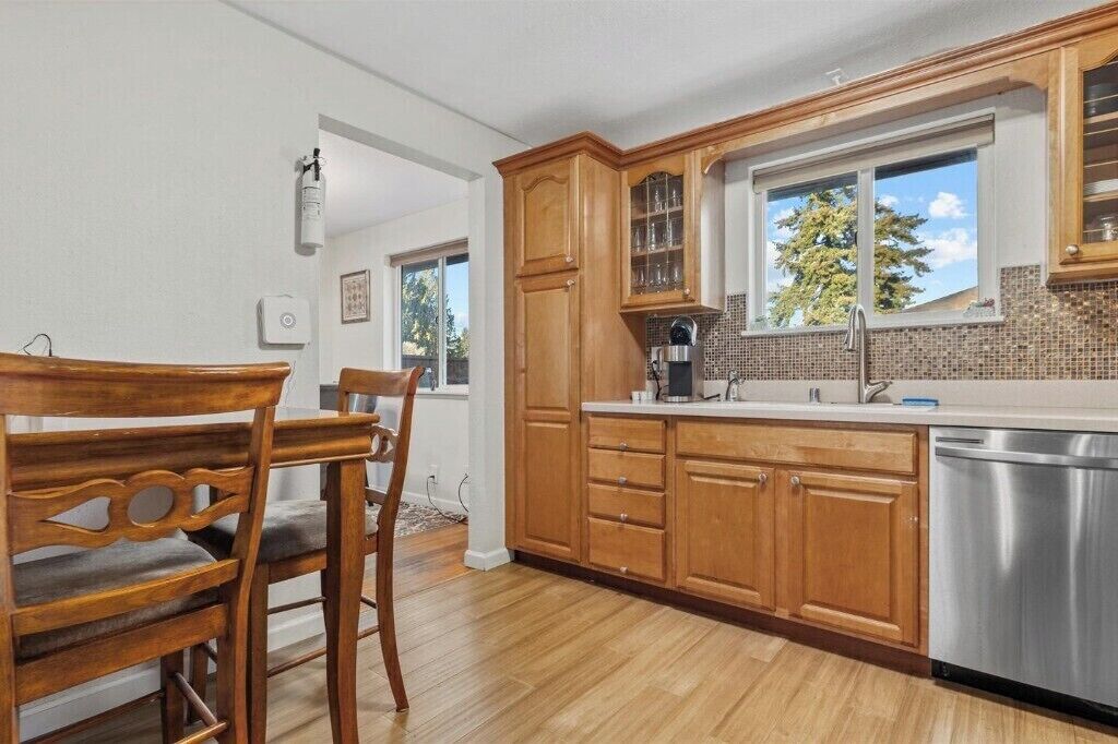 Una cucina con mobili in legno, una lavastoviglie in acciaio inossidabile e una finestra vista albero.
