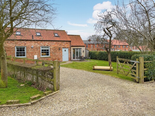 A brick house with a gravel driveway leading to a wooden gate. - Escape to this picturesque retreat in Salton, near Malton. (Salton, near Malton)