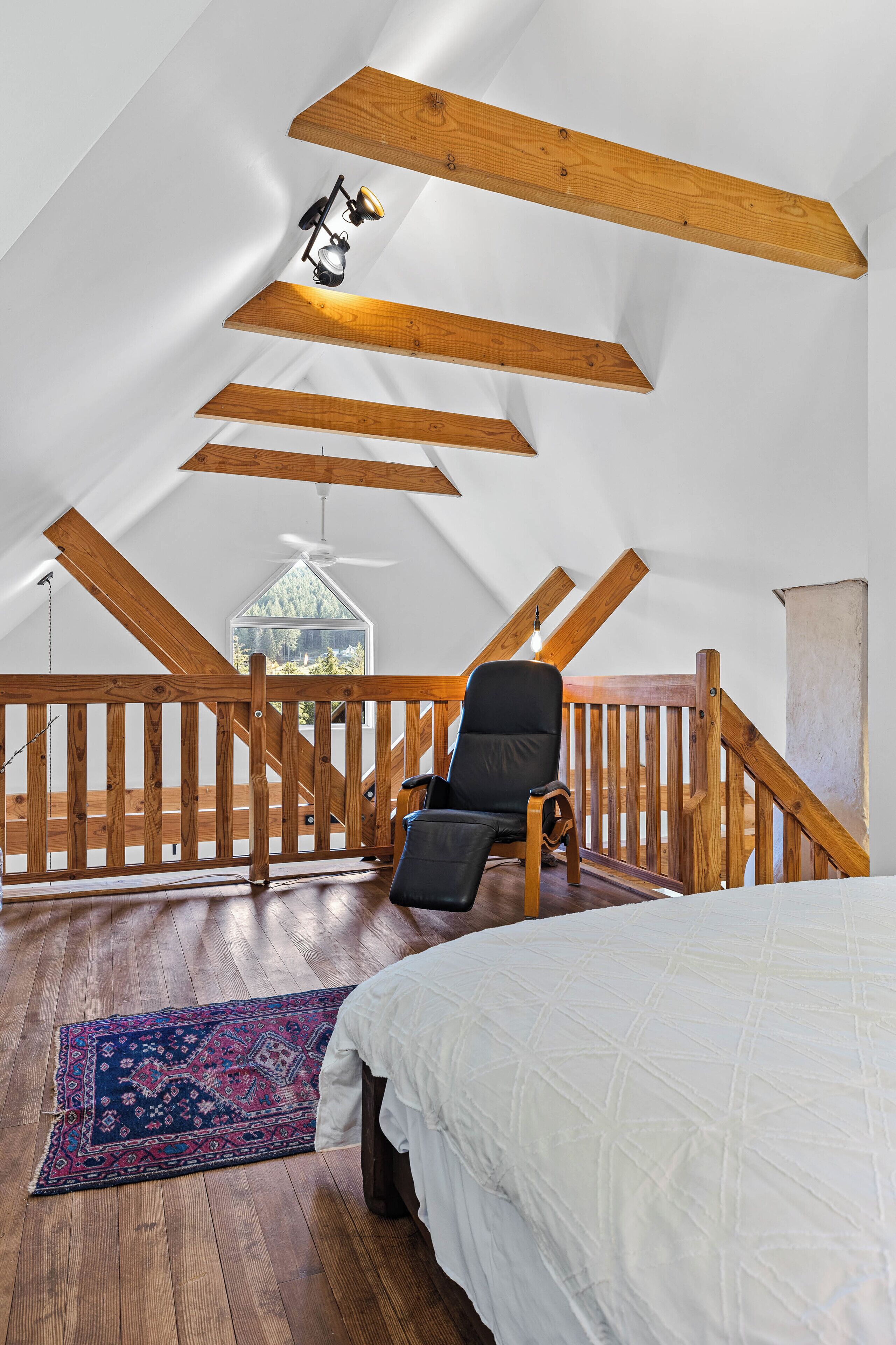 Una camera da letto con soffitto in legno, un letto, una sedia e vista sull'esterno.