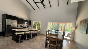 A modern kitchen with a central island, bar stools, and a dining table with chairs.
