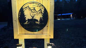 A wooden sign with a silhouette of a deer and trees, labeled "Fiddler Oaks Cabins." - Mena AR ATV Cabin Near Wolf Pen Gap & Fourche Trails Sleeps 6 Ride to Trails (Mena)