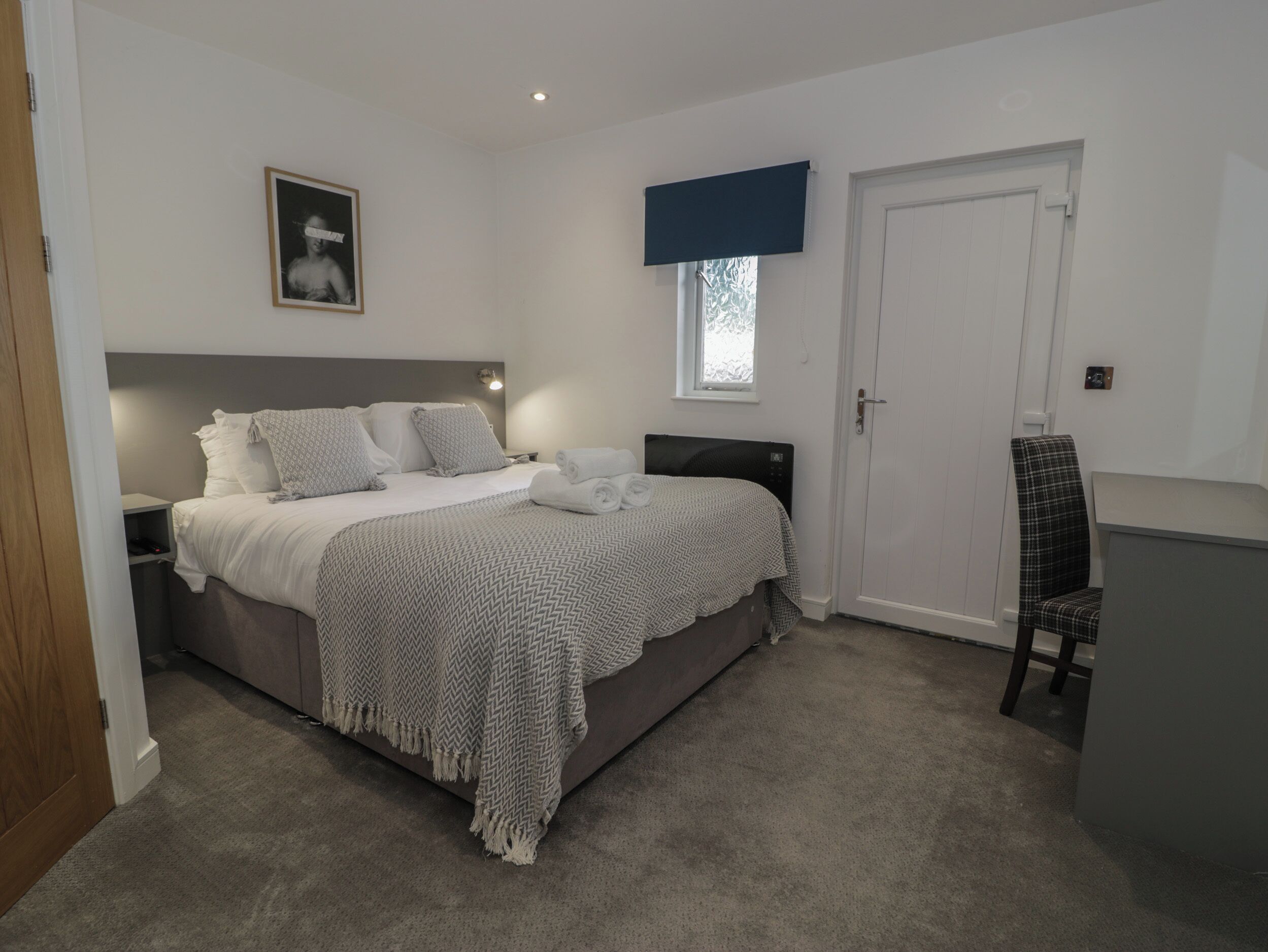 A neatly arranged bedroom with a bed, bedside table, and a chair.
