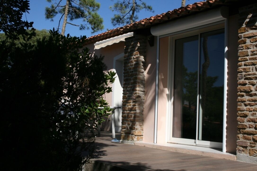 A building with a stone facade, large glass sliding doors, and a wooden deck.