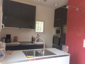 A kitchen with a white countertop, stainless steel sink, and dark cabinets.