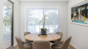 Un comedor con una mesa redonda de madera, cuatro sillas y una orquídea en maceta.