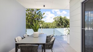 Un patio con una mesa, sillas, una planta en maceta y vistas a árboles y al cielo.