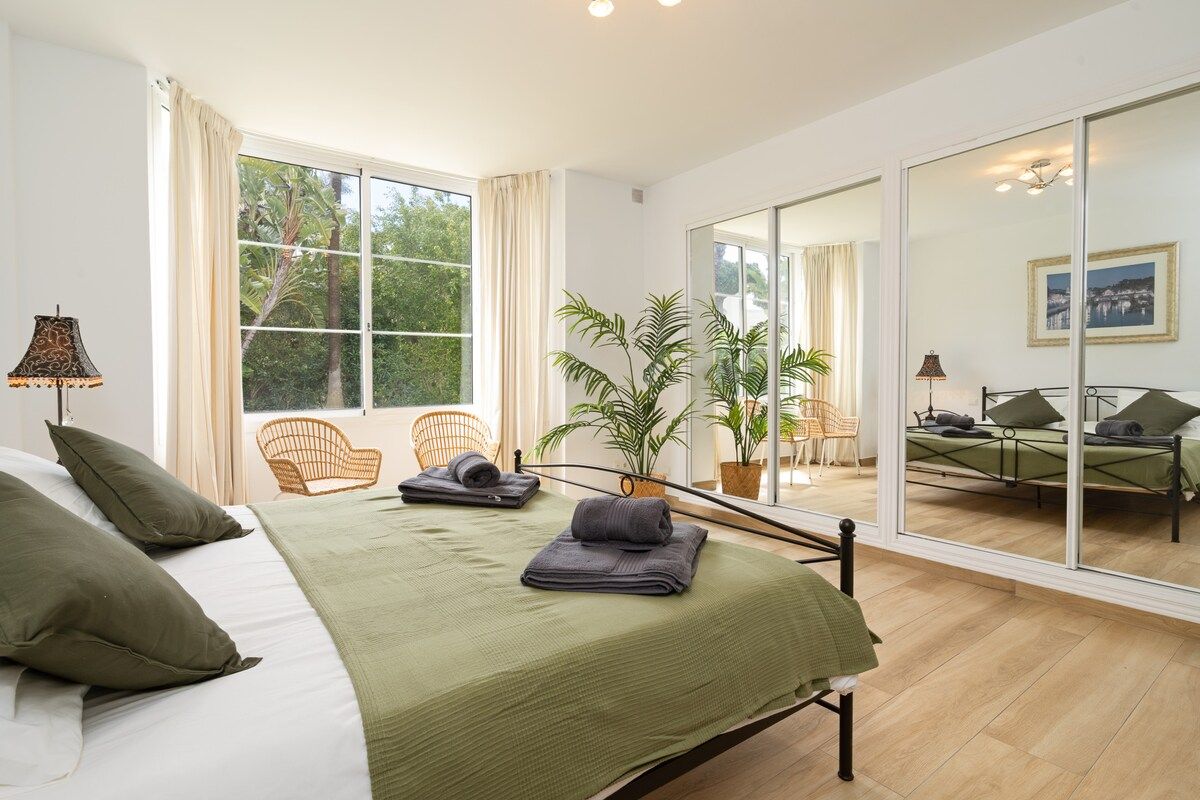 Une chambre à coucher avec un lit, une fenêtre, une chaise et une plante en pot.