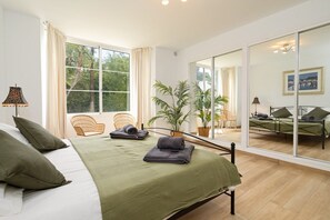 Ein Schlafzimmer mit einem Bett, einem Fenster, einem Stuhl und einer Zimmerpflanze.