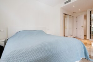 Une chambre à coucher comprenant un lit, une armoire et une porte donnant sur une autre pièce.