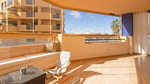 Ein geräumiger Balkon mit Sitzgelegenheit, großen Fenstern und Blick auf ein mehrgeschossiges Gebäude.