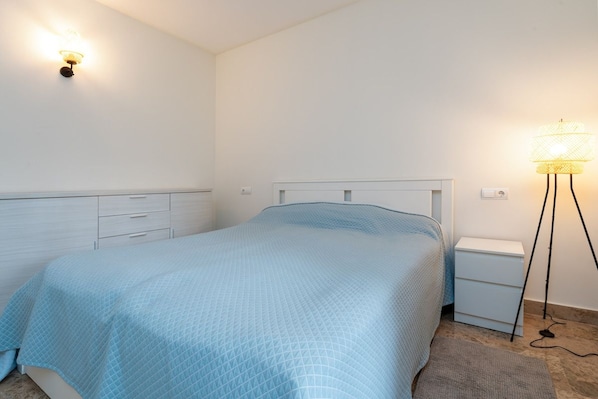 Un dormitorio con cama, mesitas de noche y una lámpara de pie.