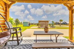 A covered patio area with a table and chairs, a small gazebo, and a view of a residential neighborhood.