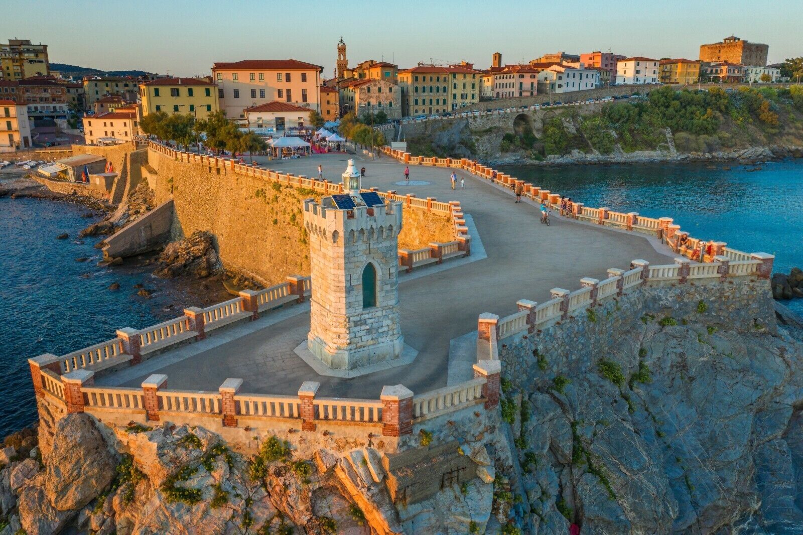 A coastal fortification with a central tower, surrounded by a fortified wall and a promenade overlooking the sea.