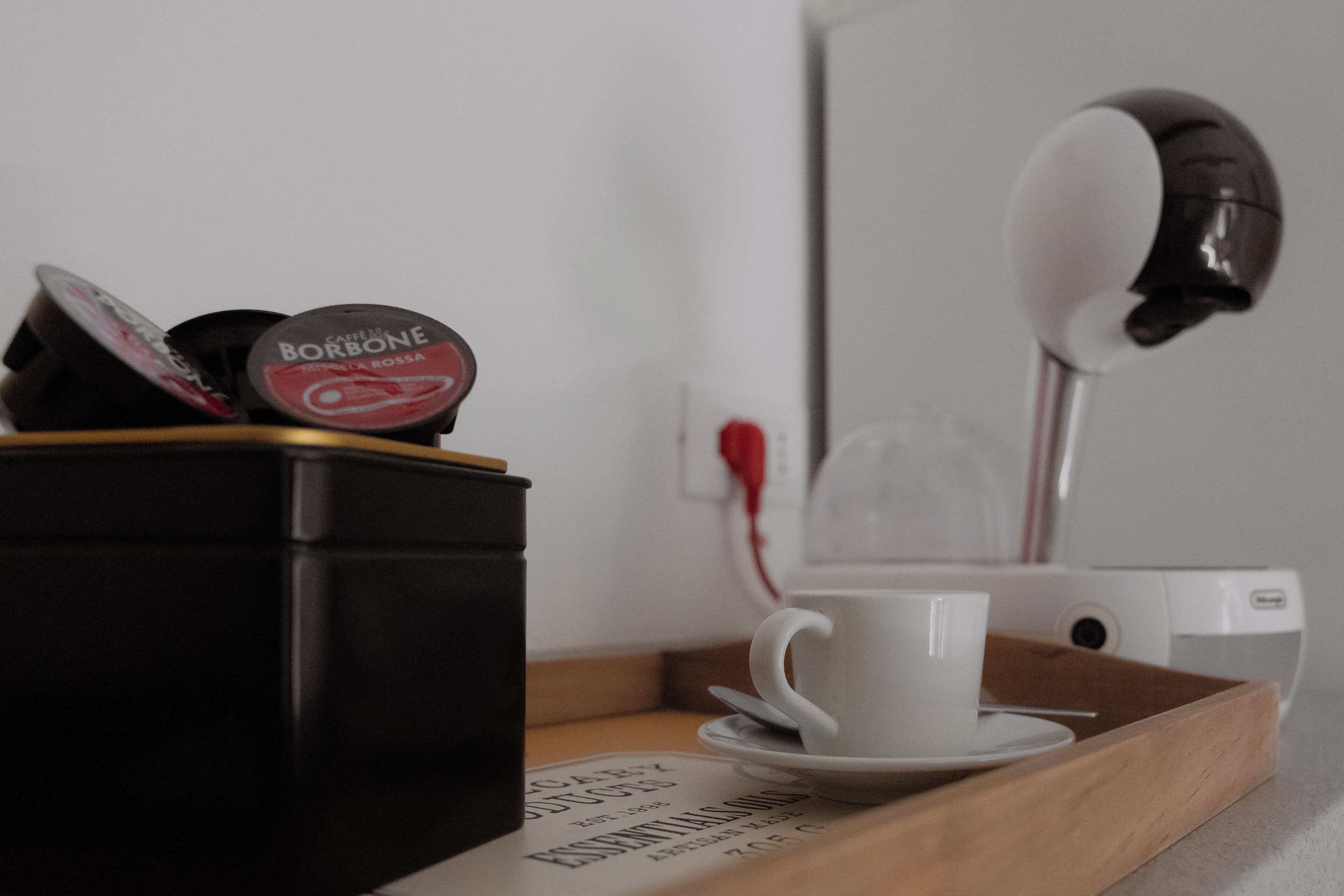 En kaffemaskin, en kopp och ett bricka med en bok på ett bord.
