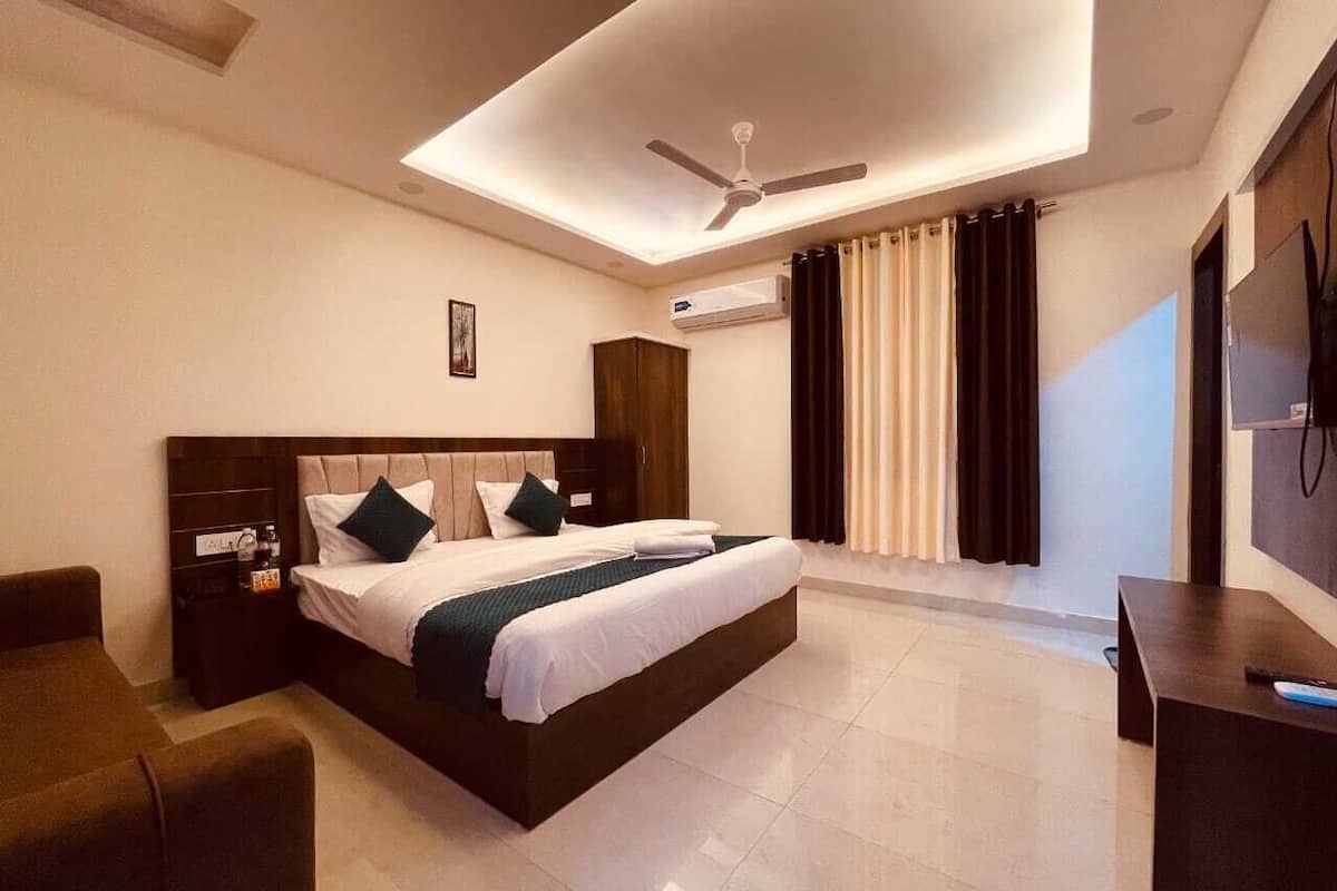 Habitación de hotel moderna con una cama grande, un escritorio, una silla, un ventilador de techo y un televisor.