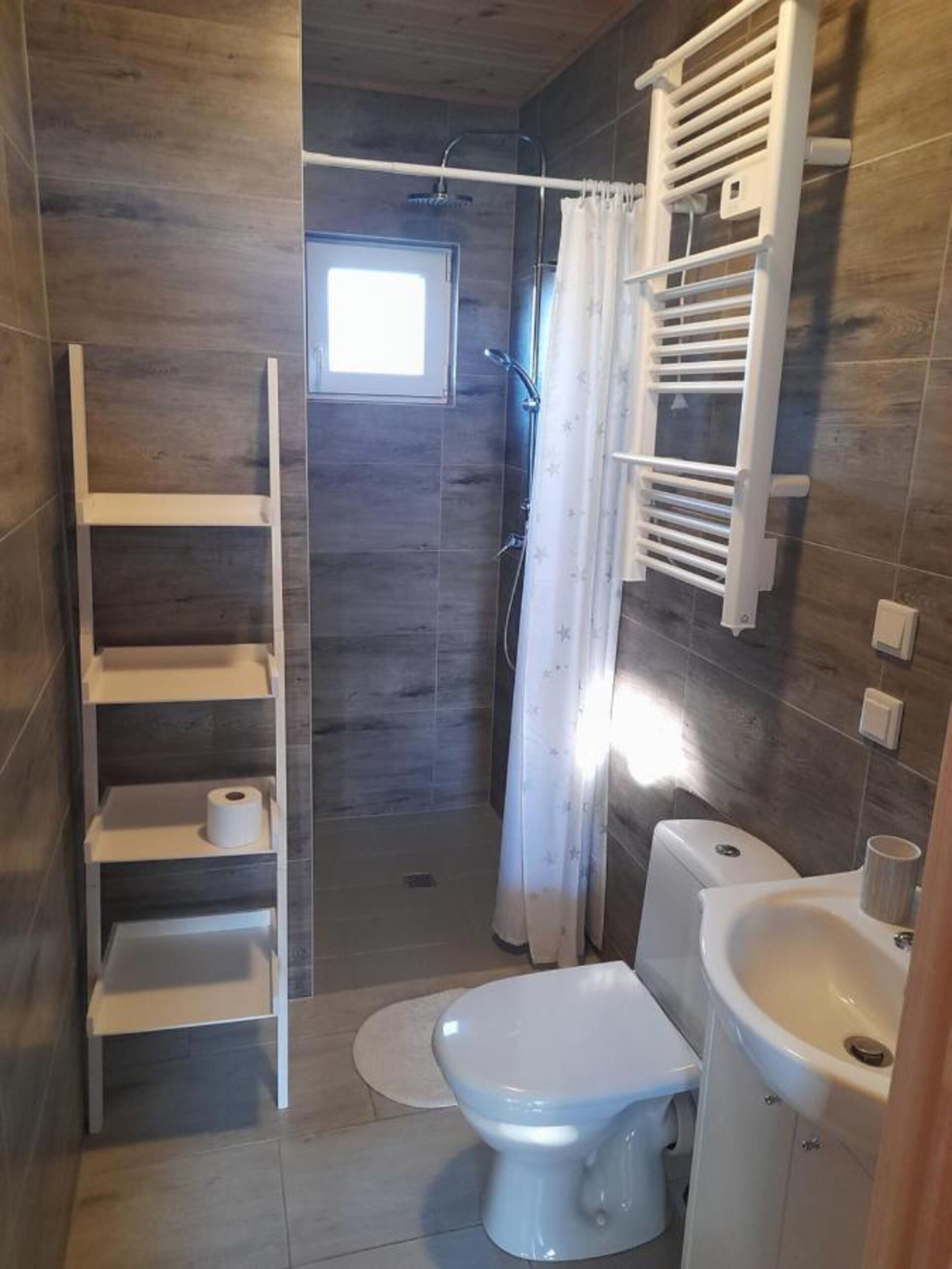 A bathroom with a shower, toilet, sink, and a window.