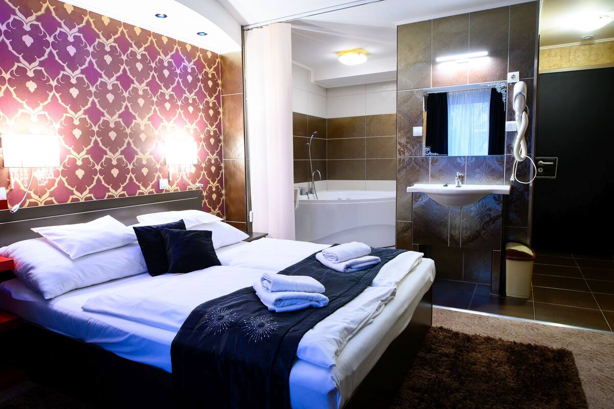 A hotel room with a large bed, a bathroom with a bathtub, and a sink.