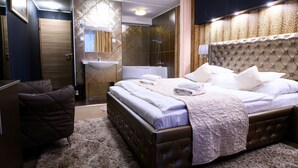 A bedroom with a large bed, a bedside table, a chair, a bathroom with a sink and shower, and a mirror. - Palermó Panzió (Nyíregyháza)