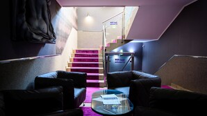 A modern interior with a staircase, leather seating, and a glass table. - Palermó Panzió (Nyíregyháza)