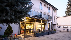 A building with a glass facade, outdoor seating, and a sign reading "Goodbye". - Palermó Panzió (Nyíregyháza)