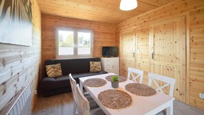 Interno di una baita in legno con divano, tavolo da pranzo e sedie.