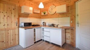 Angolo cottura compatto con pareti in legno, un forno a microonde, un bollitore e una sveglia appesa al muro.