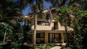 A two-story house with a covered patio, surrounded by lush greenery and palm trees. - Seahouse Beachfront B&B with Pool (Bocas del Toro)