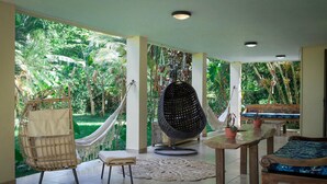 A spacious room with a hammock, a woven chair, and a wooden table. - Seahouse Beachfront B&B with Pool (Bocas del Toro)