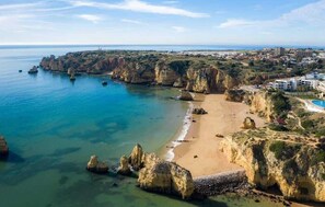 Paesaggio costiero con spiaggia, scogliere e zona turistica.