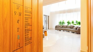 A hotel reception area with wooden paneling and a directory listing rooms and amenities. - HPaulista (São Paulo)