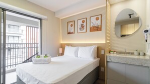 A hotel room with a bed, a bathroom with a sink, and a balcony with a railing. - HPaulista (São Paulo)