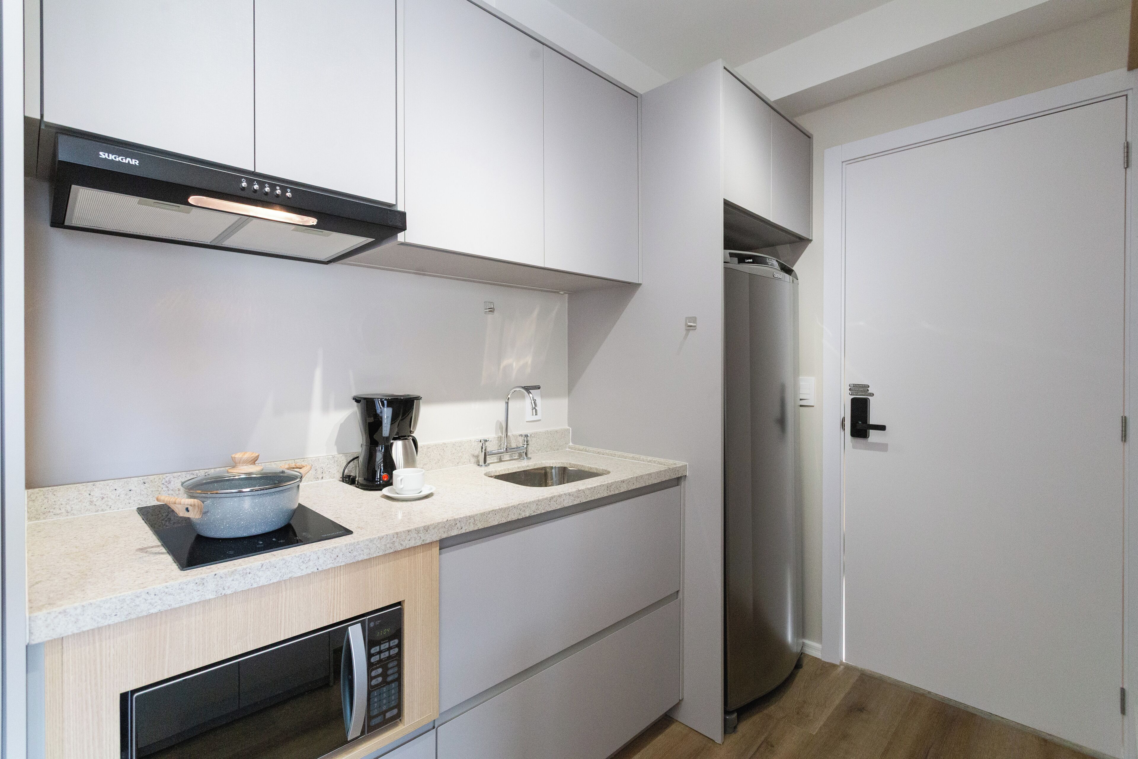 Una cocina moderna equipada con microondas, cafetera y refrigerador de acero inoxidable.