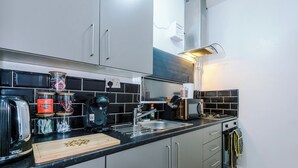 Una cocina moderna con electrodomésticos de acero inoxidable, salpicadero de azulejos blanco y negro, y armarios grises.
