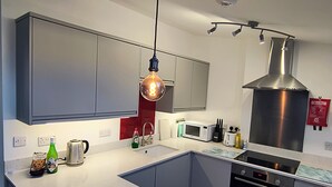 Een moderne keuken met een groot eiland, roestvrijstalen apparatuur en een hanglamp.