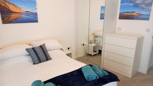 Une chambre à coucher avec un lit, une table de chevet, une commode et un miroir.