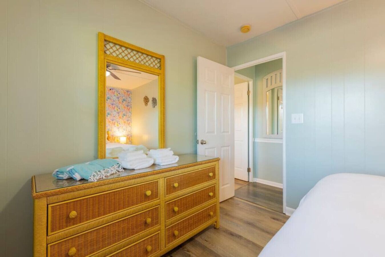 A bedroom with a wooden dresser, a mirror, and a bed.