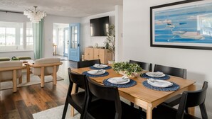 Un coin repas avec une table en bois dressée pour quatre personnes, des chaises noires et un set de table bleu.