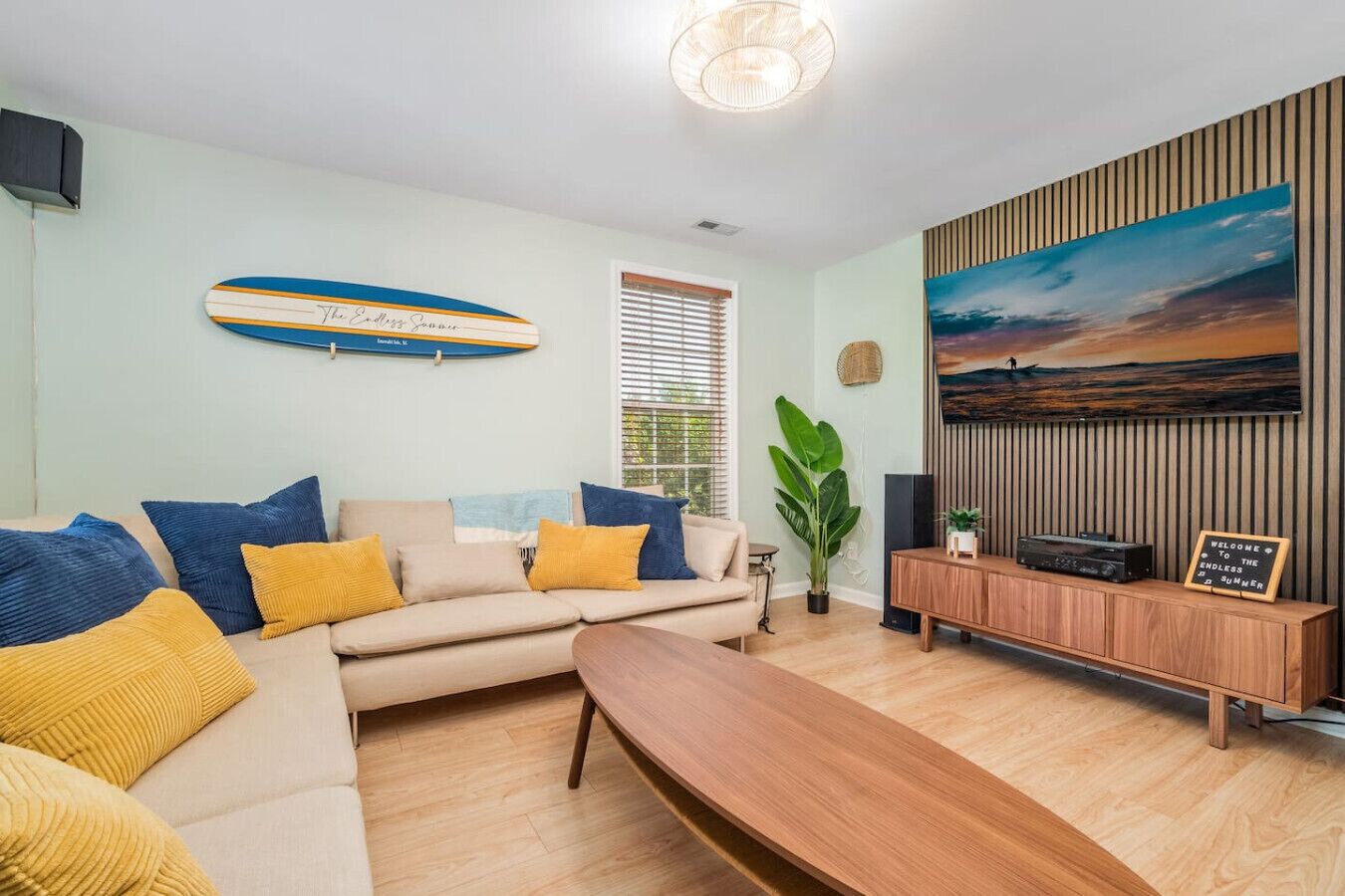 A living room with a sofa, wooden coffee table, and a painting of a sunset.
