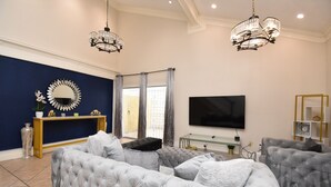 A living room with a large sectional sofa, a TV mounted on the wall, and a console table with decorative items. - EXOTIC LODGE
Discover a unique retreat experience in the heart of Houston, TX (Houston)