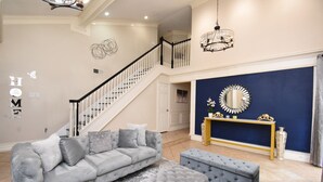 A spacious living room with a grey sofa, ottoman, and a staircase leading to an upper level. - EXOTIC LODGE
Discover a unique retreat experience in the heart of Houston, TX (Houston)
