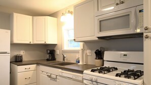 A kitchen with white cabinets, a microwave, a stove, and a dishwasher. - Spacious 3BR Retreat | Perfect for Families! (Indian River)